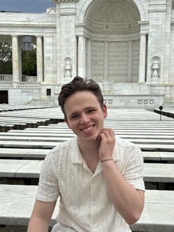 A photo of Maksym smiling with a scenic background.