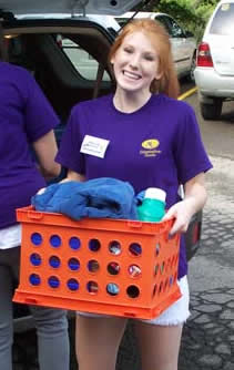 Student smiling while holding a crate of supplies