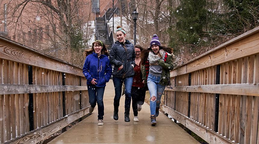 Students laughing while running in the snow