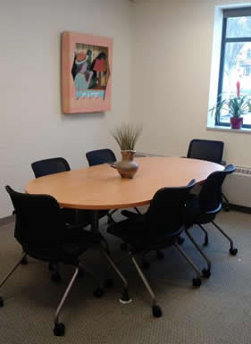 Oval table with several empty chairs around it 